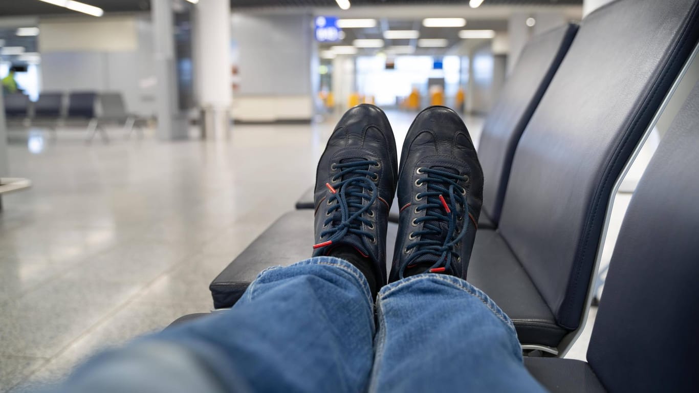 Ein Mann liegt auf einer Wartebank am Terminal (Symbolbild): Einem schlafenden Passagier am Flughafen Düsseldorf wurden die Schuhe geklaut.