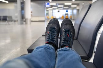 Ein Mann liegt auf einer Wartebank am Terminal (Symbolbild): Einem schlafenden Passagier am Flughafen Düsseldorf wurden die Schuhe geklaut.