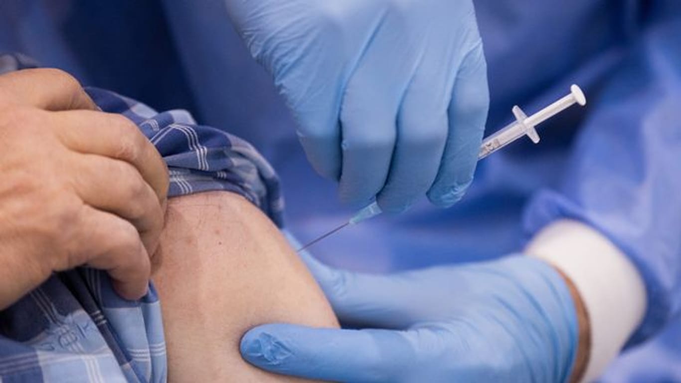 Ein Arzt impft einen Mann in einem Impfzentrum gegen Corona (Symbolbild): In Rheinland-Pfalz werden die meisten Termine zur Zweitimpfungen wahrgenommen und kaum welche abgesagt.