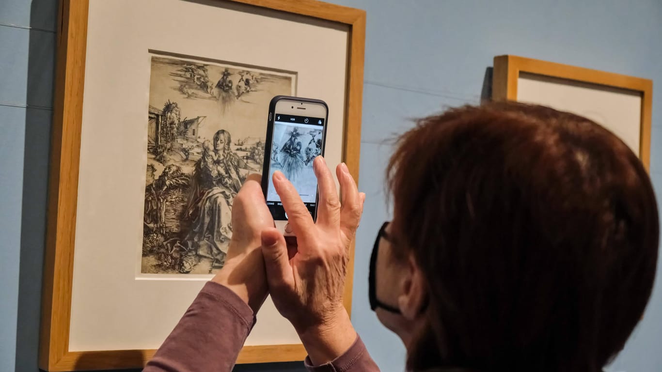 Eine Frau mit Maske fotografiert ein Bild von Albrecht Dürer in einer Ausstellung (Archivbild): Die Stadt Nürnberg feiert ihren wohl bekanntesten Bürger.