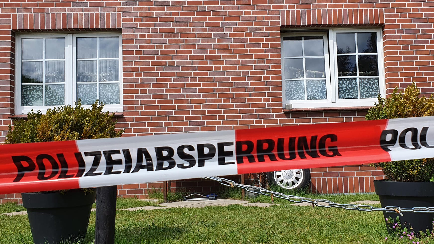 Ein Absperrband der Polizei hängt vor einem Haus: Die Polizei hat hier eine Frauenleiche und ihren toten Sohn gefunden. Ein Absperrband der Polizei hängt vor einem Haus: Die Polizei hat hier eine Frauenleiche und ihren toten Sohn gefunden.
