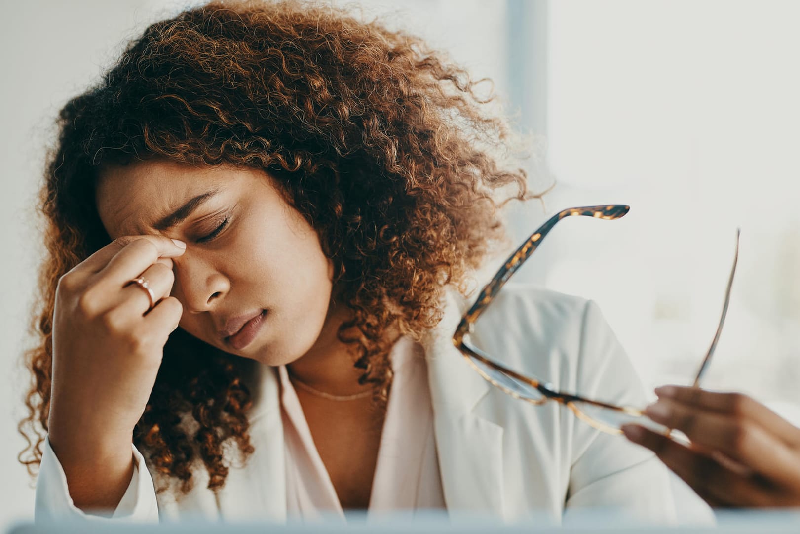 Erschöpfte Frau vor einem Computer-Display. Müde, brennende Augen sind ein Warnzeichen, dass die Augen zu trocken sind und eine Pause brauchen.