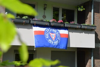 An einem Balkon hängt eine Flagge: Die Fan-Gruppe will dazu aufrufen, dass die ganze Stadt in den Farben des Vereins leuchtet.