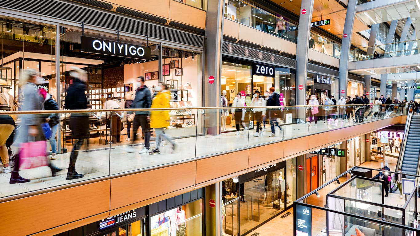 Besucher eines Einkaufszentrums in der Stadt schlendern an den Schaufenstern entlang: Die Zahl der Kunden wird anhand der Verkaufsfläche begrenzt.