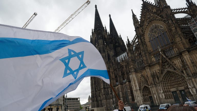 Ein Teilnehmer einer Demonstration zum Thema "Solidarität mit Israel, Solidarität mit Juden in Deutschland" hält eine Fahne Israels: Die Demos am Samstag verliefen laut Polizei störungsfrei.