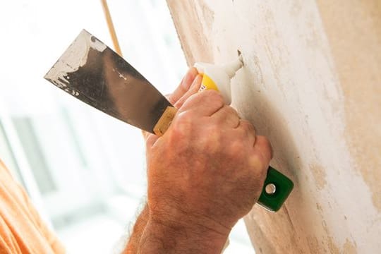 Löcher in der Wand können Heimwerker mit einer fertigen Spachtelmasse verschließen, Gips zum Anrühren ist meist günstiger.