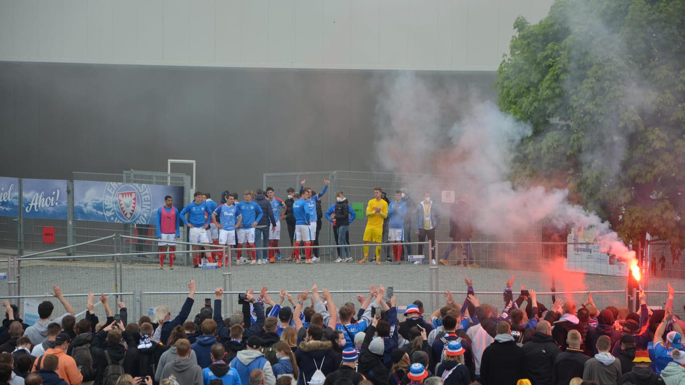 Nach dem Spiel steht die Mannschaft vor dem Stadion: Die Geste der Spieler lässt die aufgeheizte Stimmung wieder friedlicher werden.