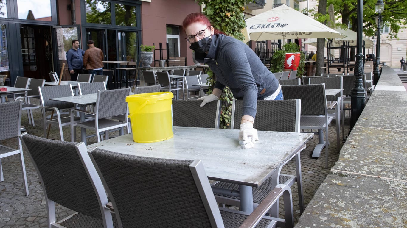 Eine Servicekraft wischt einen Tisch in einem Café ab (Symbolbild): Restaurants und Bars dürfen ihre Außenbereiche wieder öffnen.