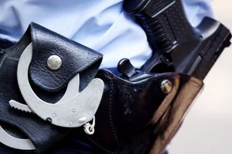 Ein Polizist mit Handschellen und Pistole am Gürtel (Symbolbild): Nach der Tat konnten zwei junge Männer festgenommen werden.
