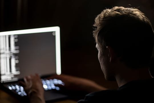 Ein Mann schreibt auf der Tastatur eines Laptops (Symbolbild): Behörden warnen vor Attacken vor der Bundestagswahl.