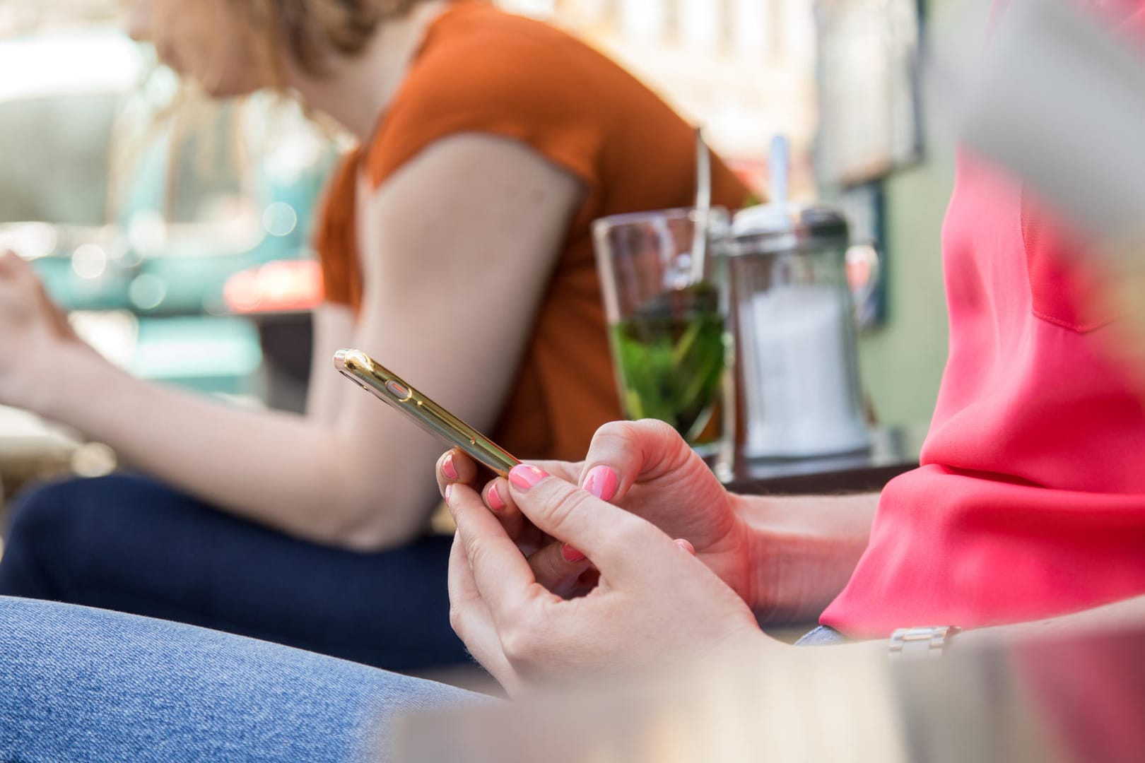 Smartphone-Nutzerinnen im Freien: Ganz sicher unsicher ist es, im offenen WLAN eines Cafés zu surfen. Abhilfe schaffen hier VPN-Dienste oder das Internet über den Mobilfunk.