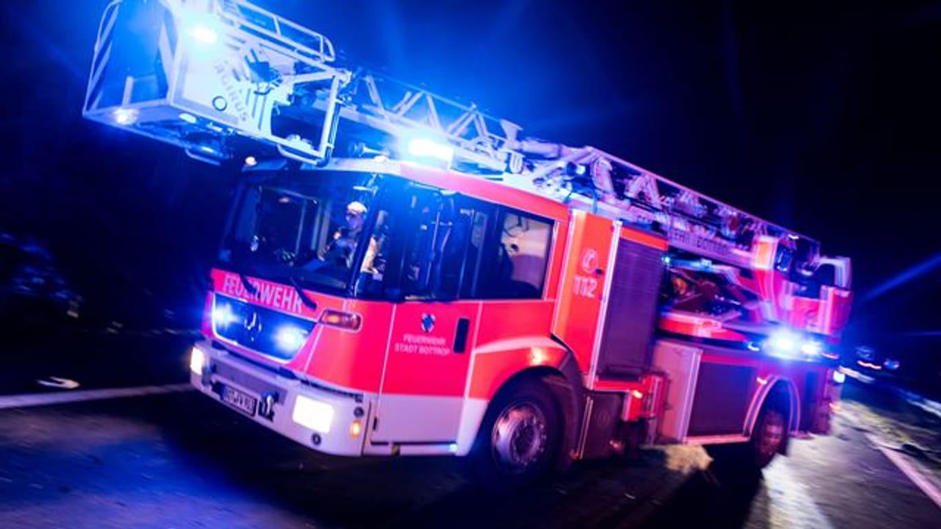 Ein Drehleiterwagen der Feuerwehr fährt zu einem Einsatz (Symbolbild): In Leverkusen wollte sich ein Mann bei einem Wohnungsbrand mit einem Sprung aus dem Fenster vor dem Feuer retten.
