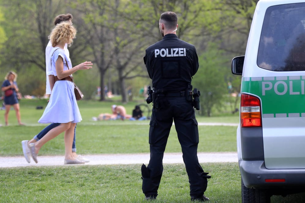 Ein Polizist steht bei schönem Wetter im Englischen Garten (Archivbild): An Sommertagen kommen Tausende in Münchens grüne Lunge, nicht immer bleibt es friedlich.