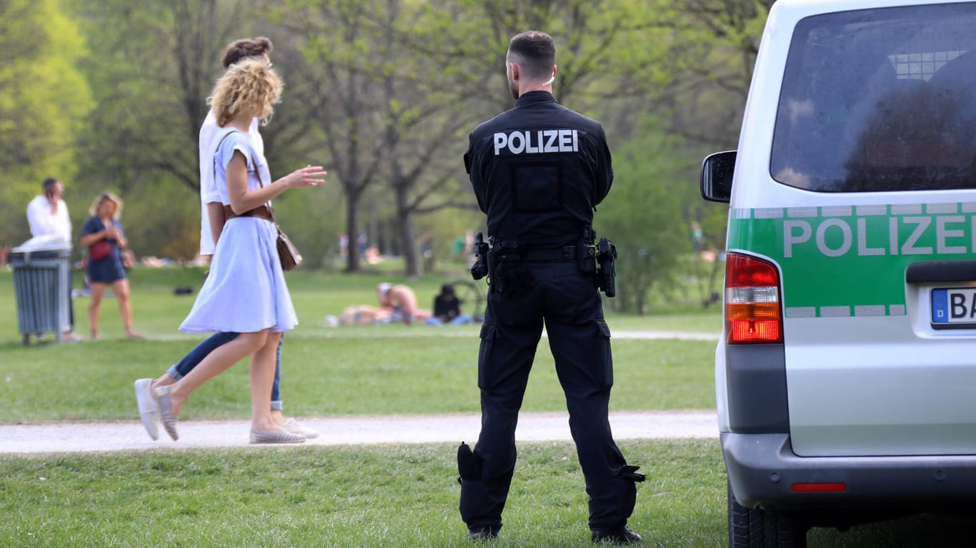 Ein Polizist steht bei schönem Wetter im Englischen Garten (Archivbild): An Sommertagen kommen Tausende in Münchens grüne Lunge, nicht immer bleibt es friedlich.