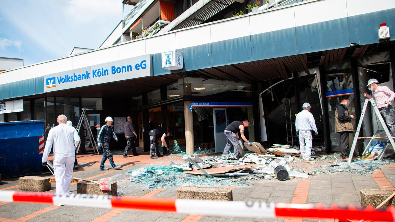 Arbeiter räumen nach der Sprengung des Geldautomaten vor einer Bankfiliale auf: Die Täter füchteten auf einem Roller.