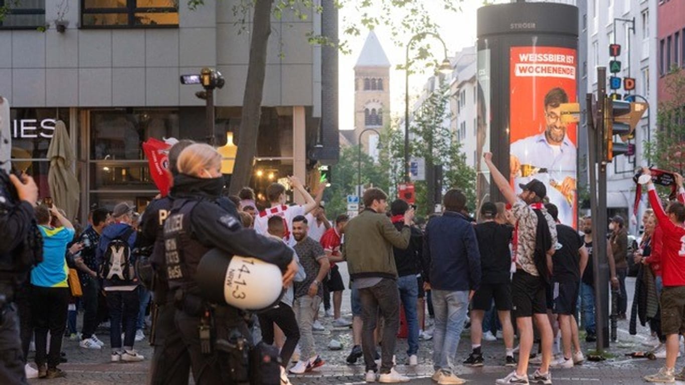 Kölner Fans hinter Polizeibeamten: Viele feierten friedlich, manche jedoch missachteten Corona-Regeln.