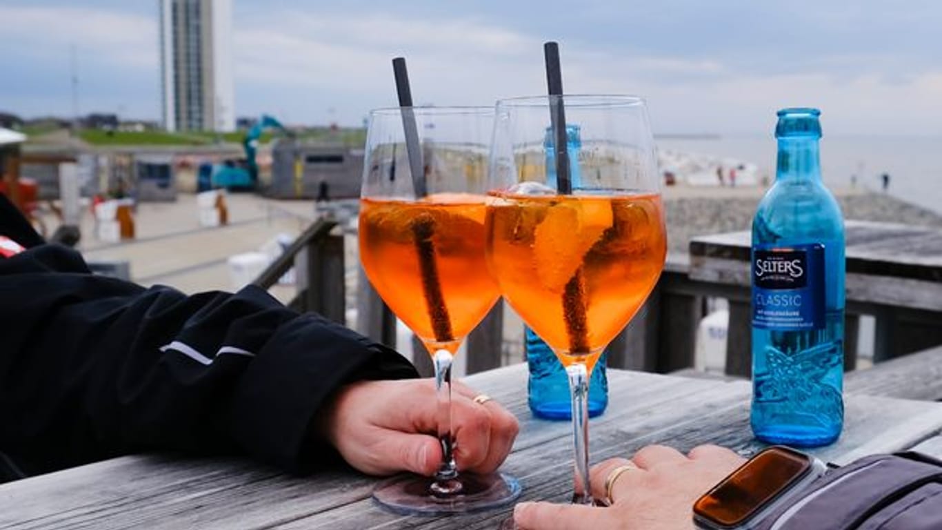 Ein Mann und eine Frau stoßen mit ihren Getränken an (Archivbild): In Schleswig-Holstein gelten nun andere Corona-Regeln.