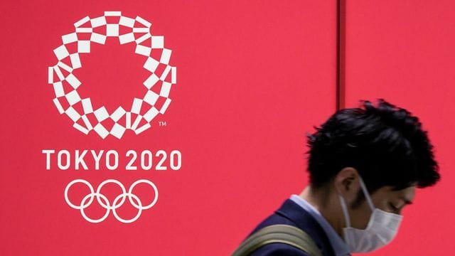 Von Euphorie ist in Japan vor den Sommerspielen wenig zu spüren: Ein Mann mit Mund-Nasen-Schutz geht an einem Werbeplakat vorbei.