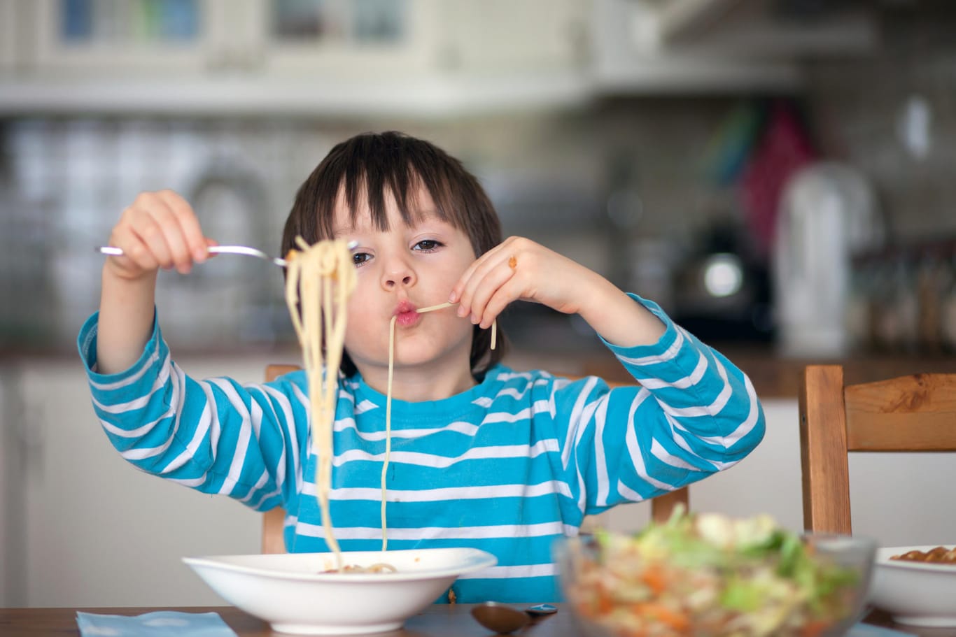 Ein Junge isst Spaghetti: Warum man nicht mit Essen spielt, müssen Kinder erst verstehen.