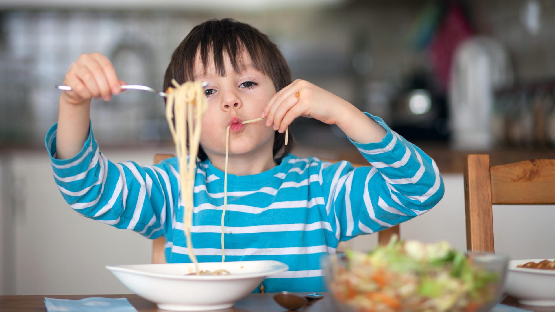 Ein Junge isst Spaghetti: Warum man nicht mit Essen spielt, müssen Kinder erst verstehen.