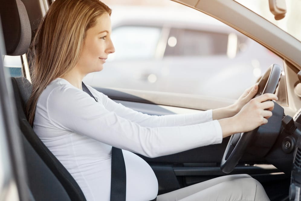 Eine Schwangere fährt Auto: Auch werdende Mütter sollten sich beim Autofahren anschnallen, um sich und ihr Kind zu schützen.