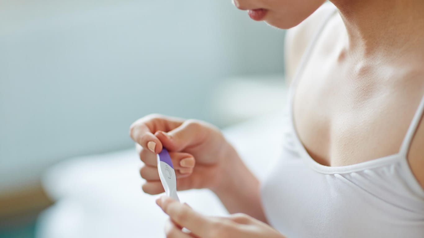 Eine junge Frau mit Schwangerschaftstest in der Hand: Ein Schwangerschaftstest kann Ihnen innerhalb von Sekunden anzeigen, ob Sie schwanger sind.
