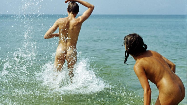 Junges Paar badet nackt im Meer: FKK ist nicht überall gerne gesehen. Urlauber sollten sich vorher informieren.