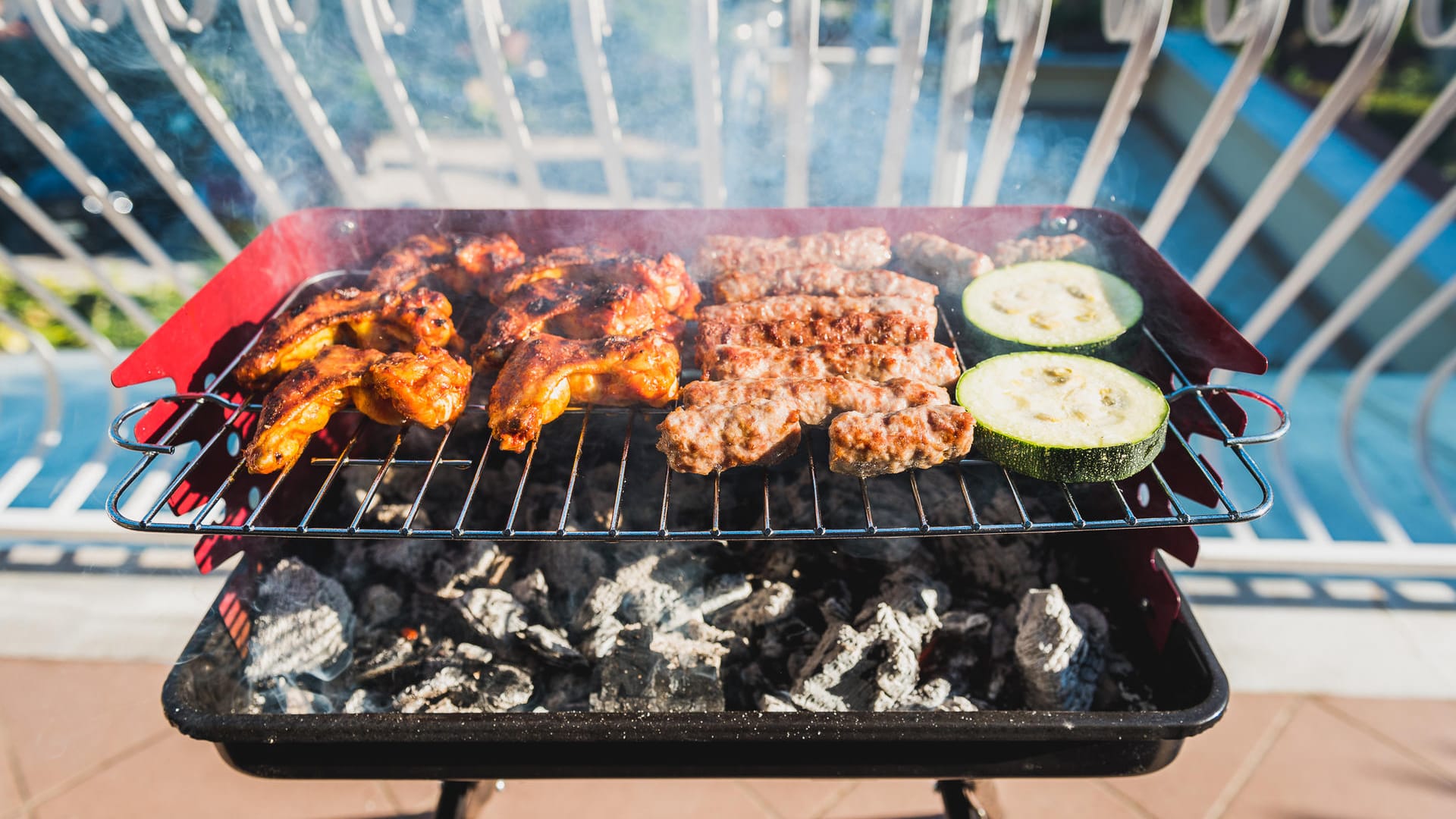 Delicious meat on barbecue grill with coal on balcony.