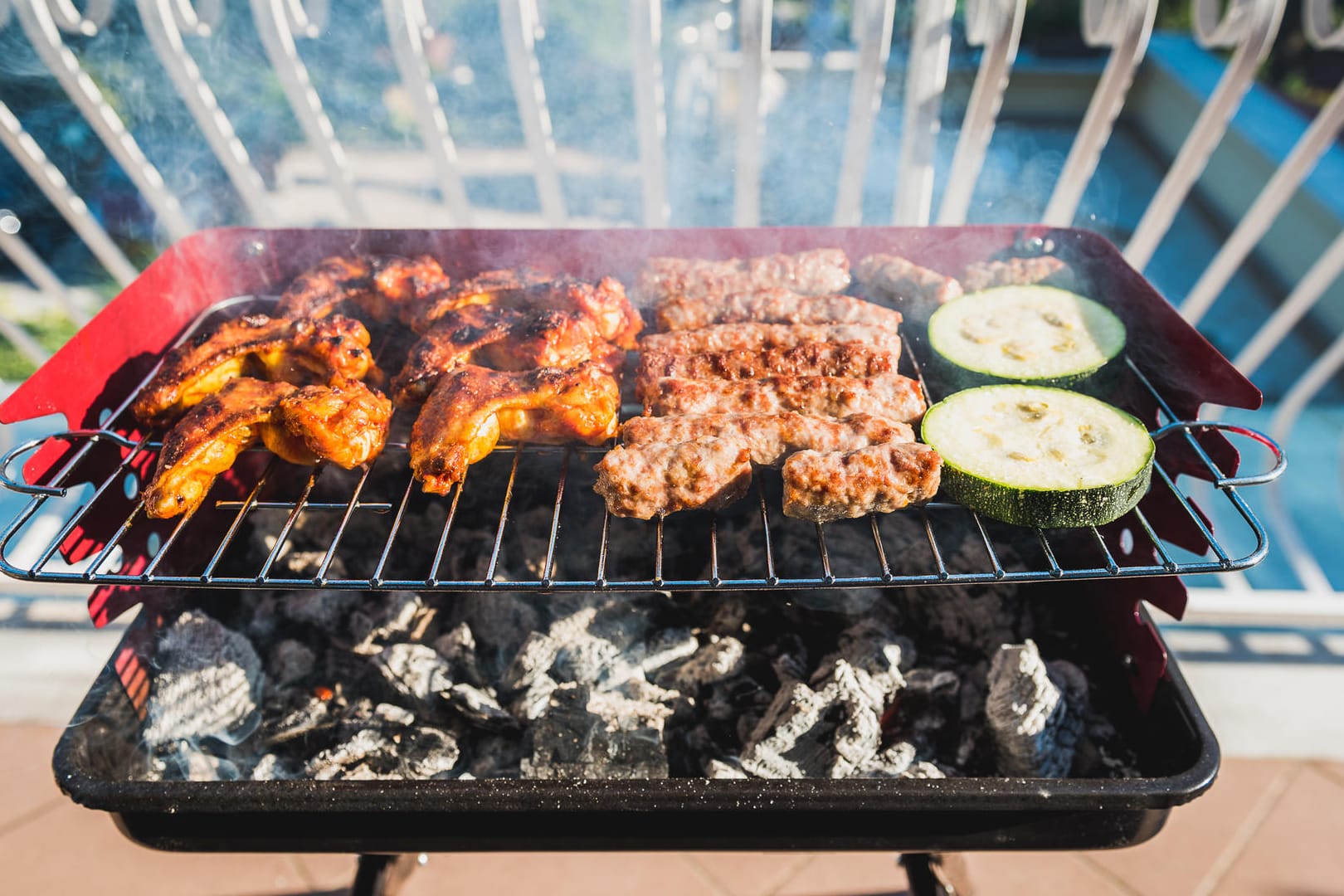 Delicious meat on barbecue grill with coal on balcony.