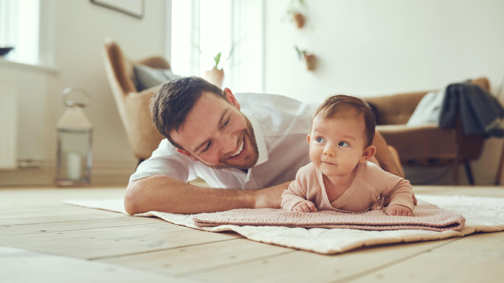 Smiling father lying with his infant daughter at home