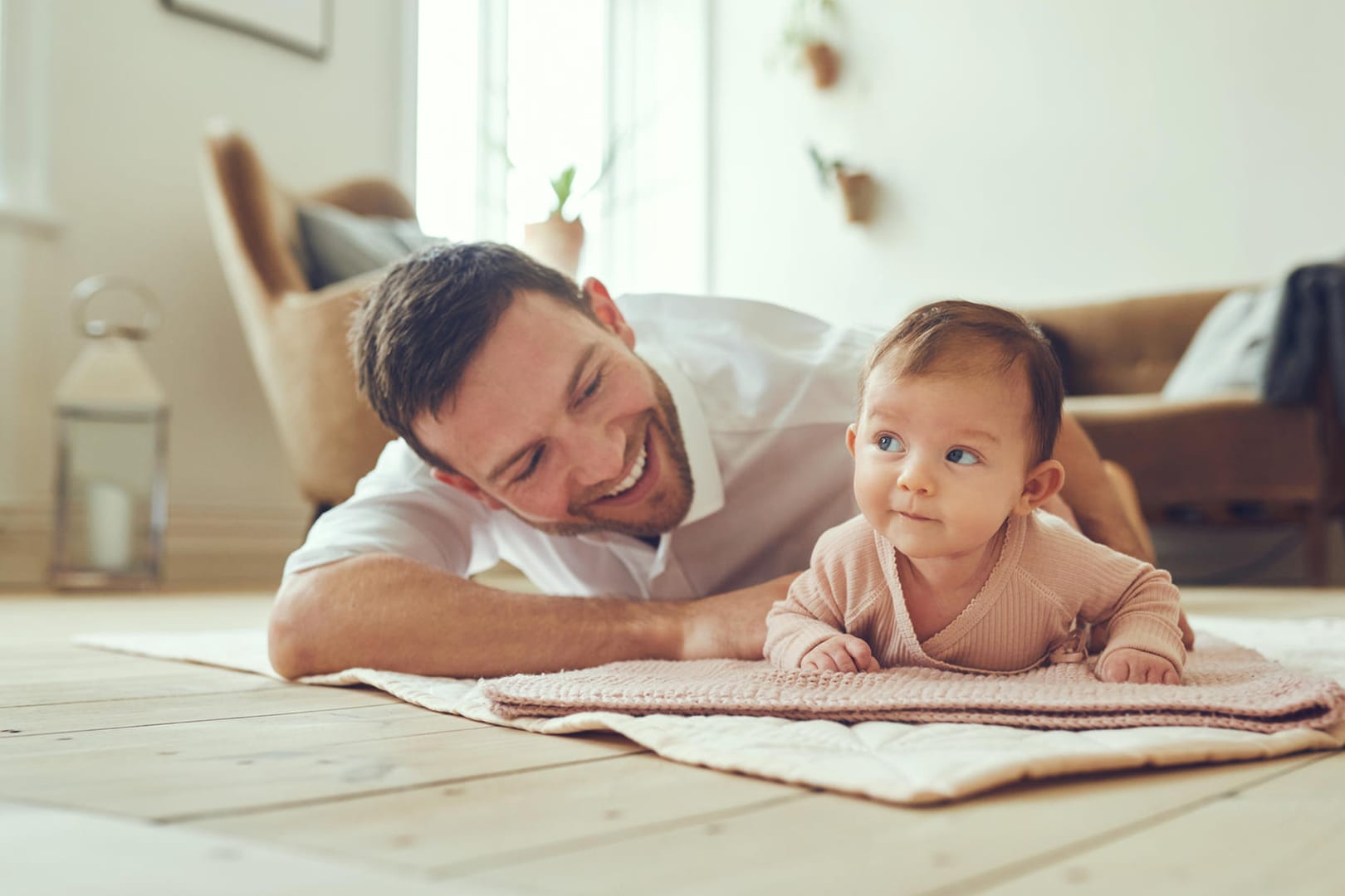 Smiling father lying with his infant daughter at home