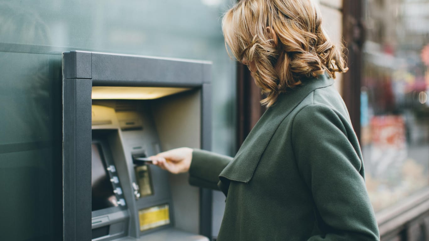 Eine Frau nutzt einen Geldautomaten (Symbolbild): Wer Bargeld abheben möchte, benötigt dafür ein eigenes Konto.
