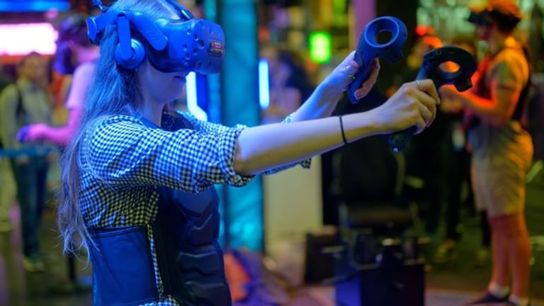 Eine Besucherin testet auf der Gamescom mit einer VR-Brille ein Computerspiel.