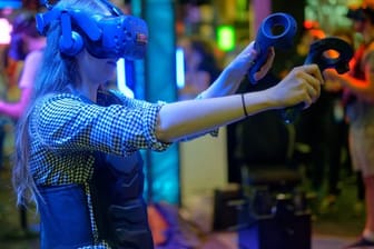 Eine Besucherin testet auf der Gamescom mit einer VR-Brille ein Computerspiel.