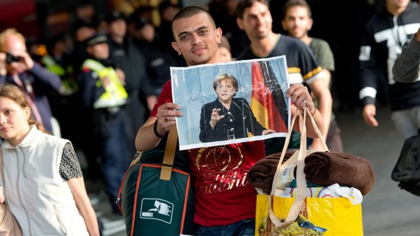 Ein Flüchtling, der kurz zuvor mit einem Zug angekommen ist, hält voller Hoffnung ein Foto von Angela Merkel in den Händen.