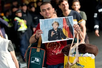 Ein Flüchtling, der kurz zuvor mit einem Zug angekommen ist, hält voller Hoffnung ein Foto von Angela Merkel in den Händen.
