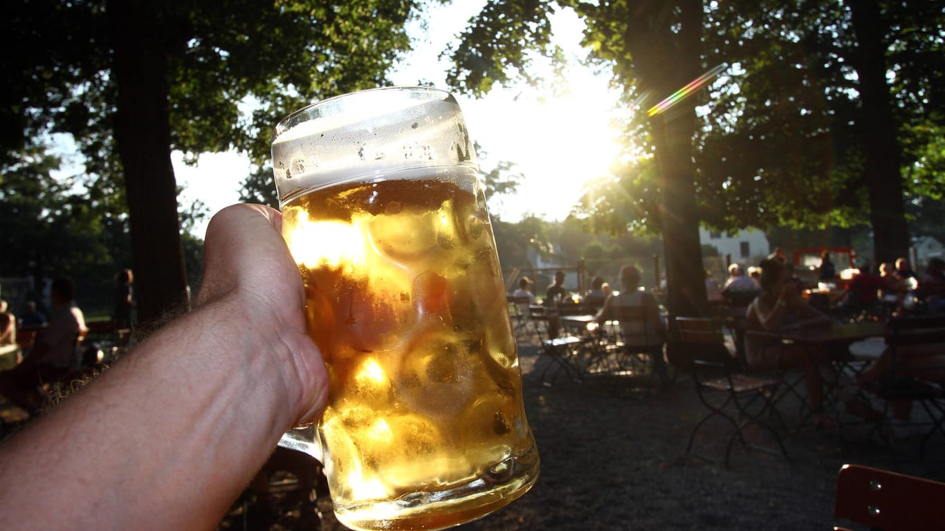 Eine Hand hält ein Bier gegen die tiefstehende Abendsonne (Symbolbild): Der Verzehr von Alkohol wird in München eingeschränkt.