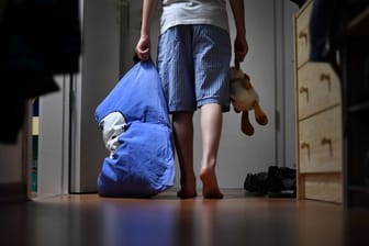 Eine Kind geht mit einem Kuscheltier durch die dunkle Wohnung (Symbolbild): Ein 54-Jähriger soll seine Internet-Bekanntschaft zum Missbrauch ihrer eigenen Kinder überredet haben.