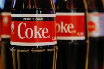 Coca-Cola-Flaschen stehen in einer Reihe: Der Getränkehersteller will sich von tausenden Mitarbeitern trennen.
