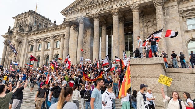 Teilnehmer einer Kundgebung gegen die Corona-Maßnahmen stehen auf den Stufen zum Reichstagsgebäude, zahlreiche Reichsflaggen sind zu sehen. Teilnehmer einer Kundgebung gegen die Corona-Maßnahmen stehen auf den Stufen zum Reichstagsgebäude, zahlreiche Reichsflaggen sind zu sehen.