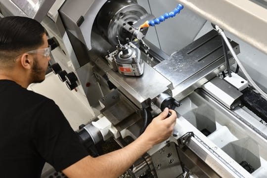 Der angehende Industriemechaniker Mohammed Elosrouti bearbeitet an der Drehmaschine ein Werkstück.