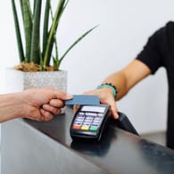 Ein Kunde hält eine Kreditkarte an ein Bezahlterminal: Forscher haben Visas PIN-Verfahren geknackt.