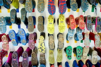 Gummistiefel von Kindern an der Wand einer Kita.