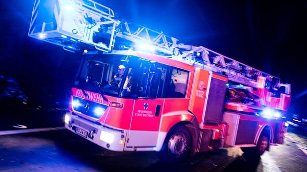 Ein Drehleiterwagen der Feuerwehr ist mit Blaulicht im Einsatz