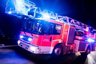 Ein Drehleiterwagen der Feuerwehr ist mit Blaulicht im Einsatz