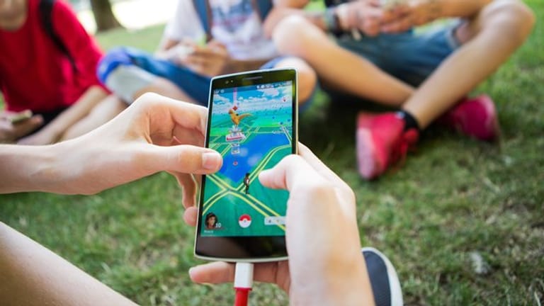 Jugendliche spielen in einem Park das Smartphone-Spiel "Pokemon Go".