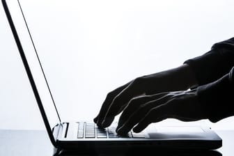 Eine Person tippt auf der Tastatur eines Laptops.