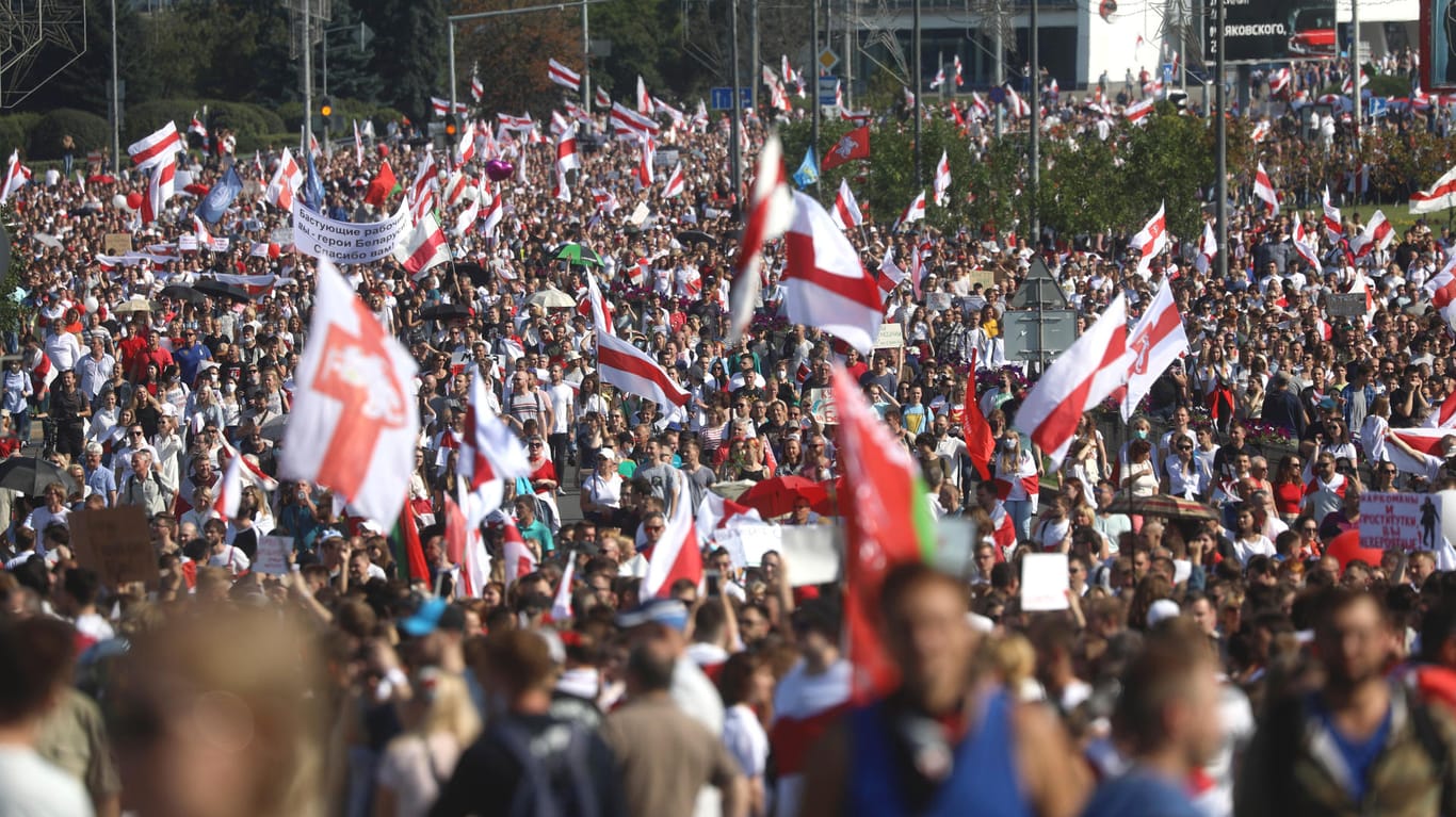 Minsk: Demonstranten marschieren mit der ehemaligen belarussischen Nationalflagge auf der Straße.