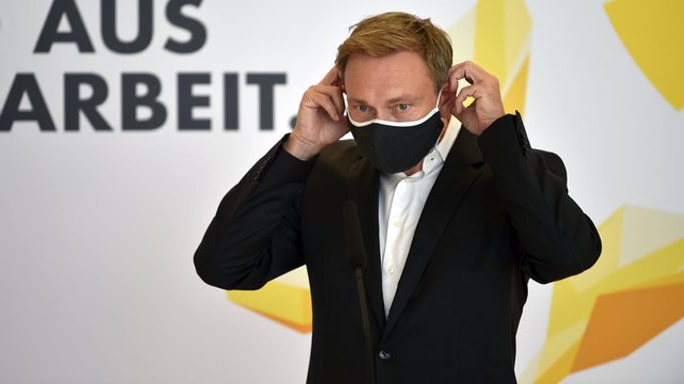 Christian Lindner, Bundesvorsitzender der FDP, legt einen Mund-Nasen-Schutz auf einer Pressekonferenz an.