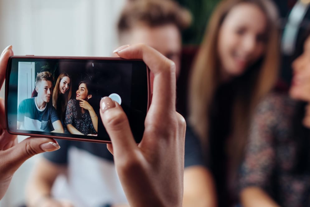 Eine Frau macht mit dem Smartphone ein Foto von ihren Freunden: Connect hat untersucht, welche Geräte die beste Bildqualität liefern.